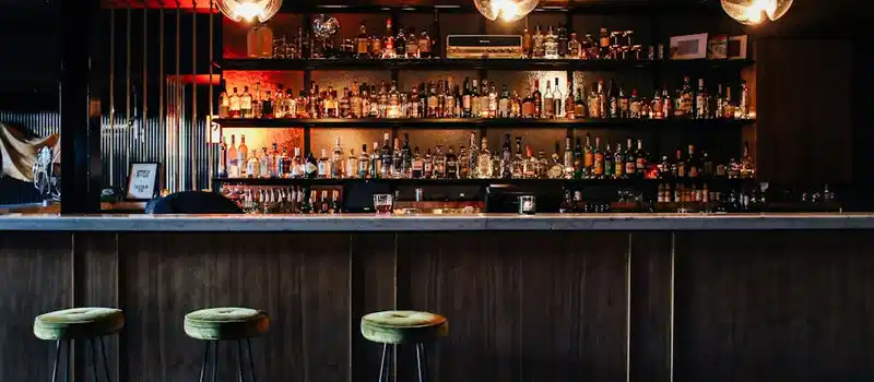 Elegant empty bar counter with stylish lighting and a wide range of beverages on display.