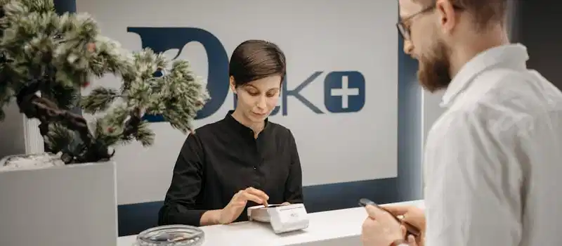 Customer makes a cashless payment at a clinic reception using wireless technology.