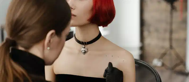 Tattoo artist creating body art on a woman with red hair in a studio.