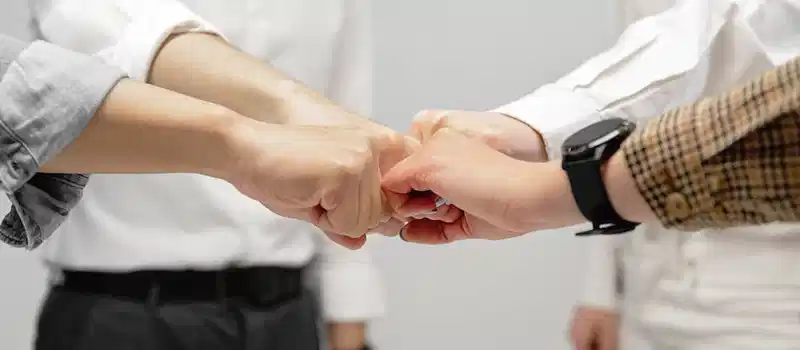 Close-up of diverse team members doing a fist bump indoors, symbolizing unity and teamwork.