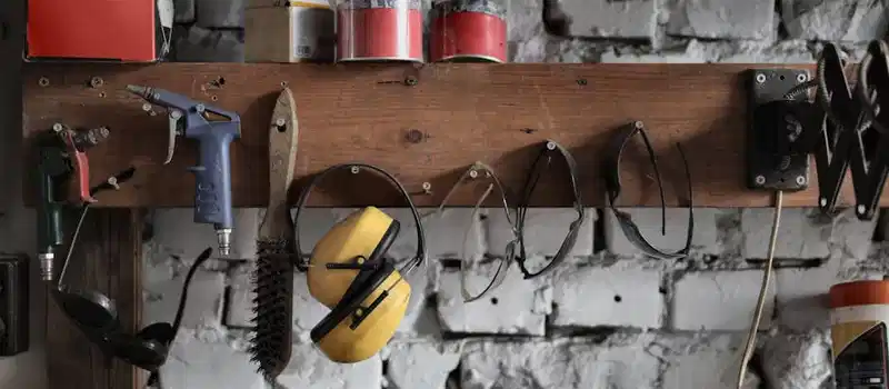 A collection of assorted industrial tools and safety gear arranged in a rustic workshop setting.
