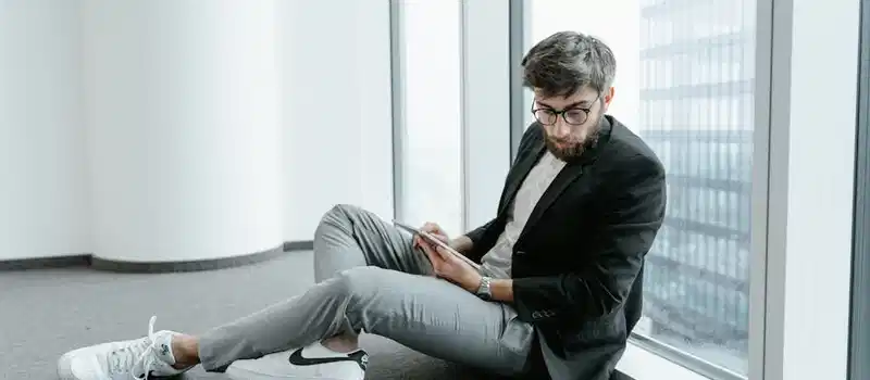 A man in an office setting using a tablet to analyze stock market data with graphs.