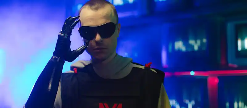 Portrait of an individual in futuristic gear, featuring a prosthetic arm and sunglasses.