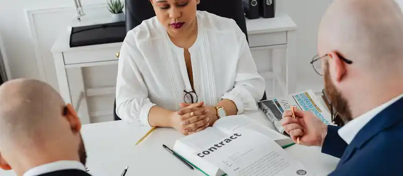 Professionals discuss a contract in a modern office setting, focusing on agreement details.