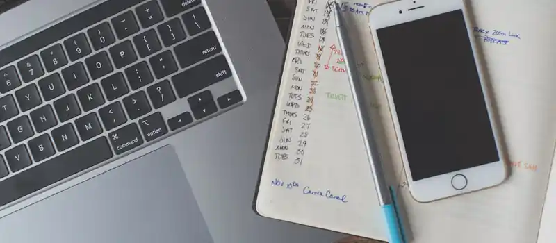 A workspace featuring a laptop, smartphone, and planner on a wooden desk, ideal for remote work.