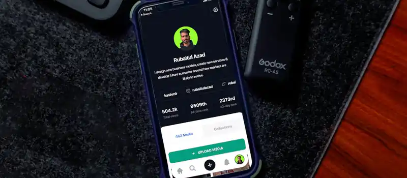 Smartphone on desk showing social media profile page with keyboard and remote nearby.