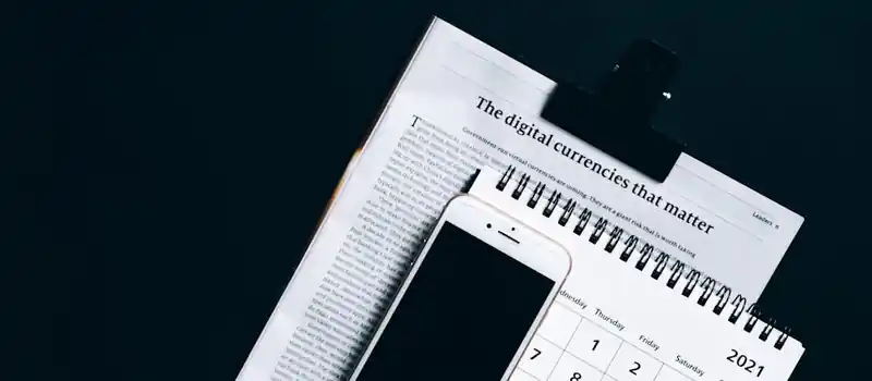 A smartphone placed on a newspaper and calendar, symbolizing modern digital finance.