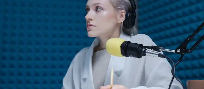 Confident woman wearing headphones hosting a podcast in a soundproof studio.