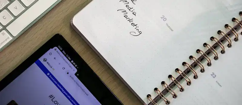 Top view of a notebook, tablet, and keyboard used for social media marketing planning.