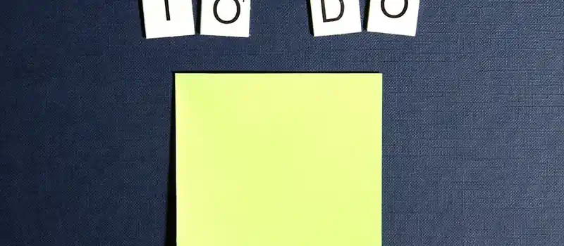 A blank sticky note displayed under scrabble tiles spelling 'To Do' on a blue background.