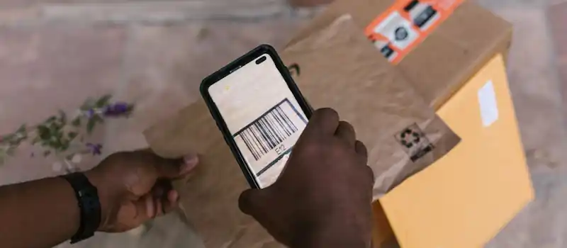 A person scans package barcodes using a smartphone for delivery logistics.