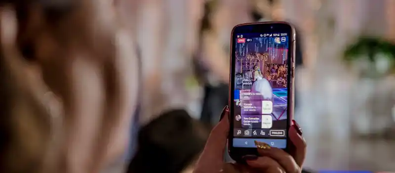 A woman captures a live event video using a smartphone at a lively indoor gathering.