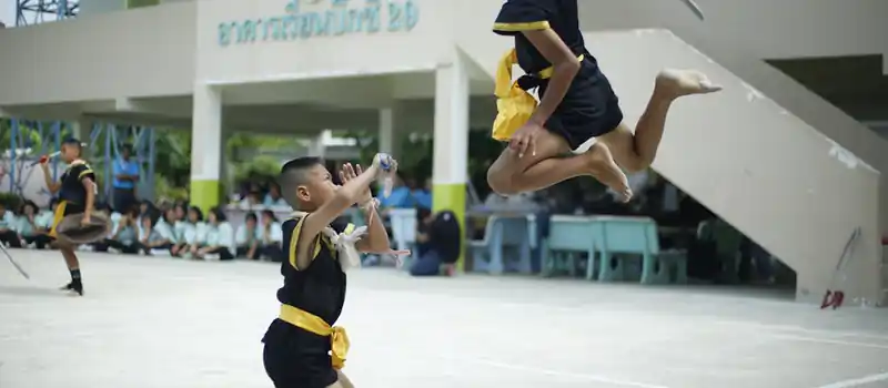 Energetic swordplay by young martial artists in a public demonstration setting.