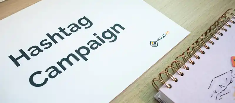 A clean office desk setup featuring hashtag campaign marketing materials and a planner.