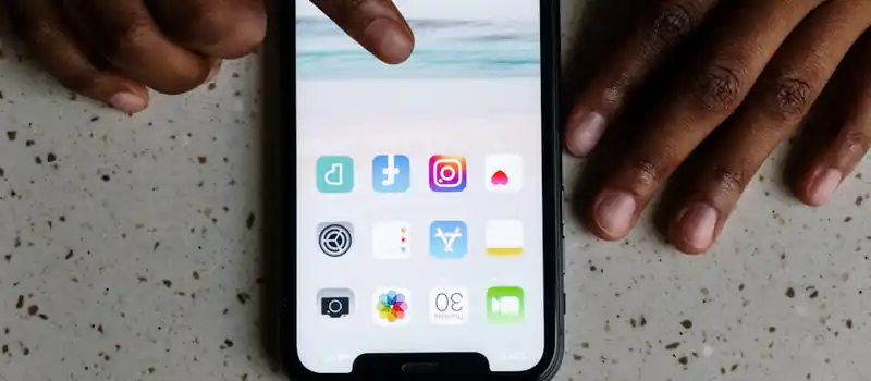 Close-up view of hands interacting with social media apps on a smartphone screen.