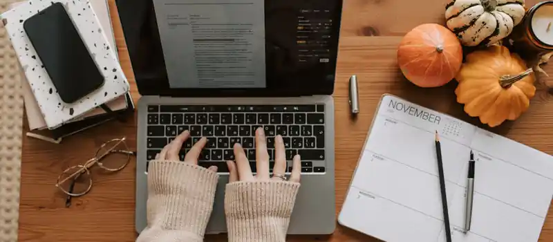 A cozy autumn-themed desk setup with a laptop and planner for productive work sessions at home.