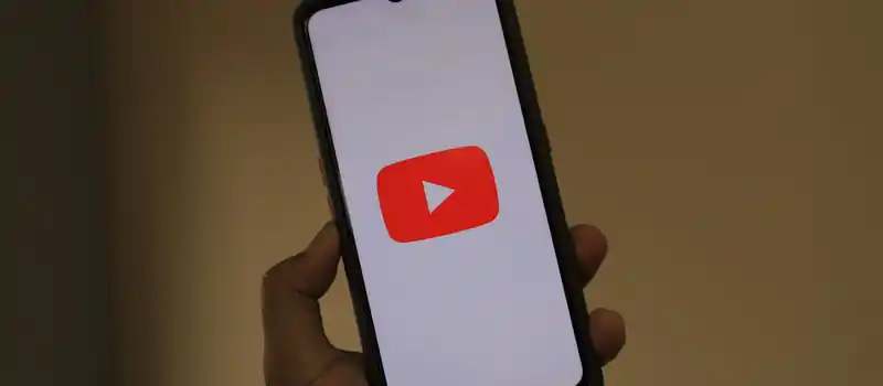 Close-up of a smartphone displaying the YouTube app logo on the screen.