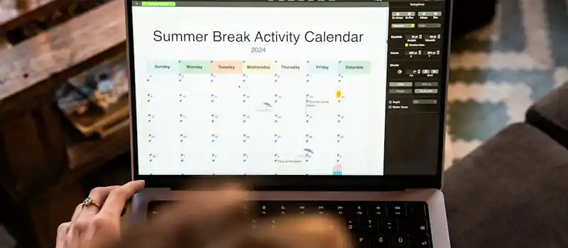 A woman uses a laptop to organize a 2024 summer break activity calendar from home.