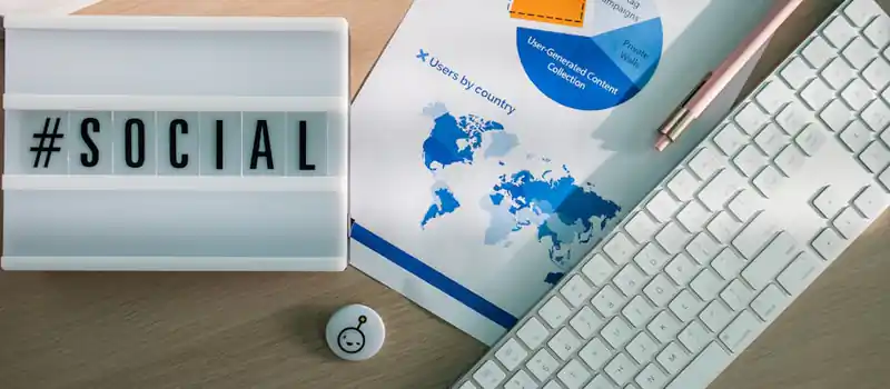 Top view of a desk with social media hashtag, keyboard, and analytics chart in modern design.