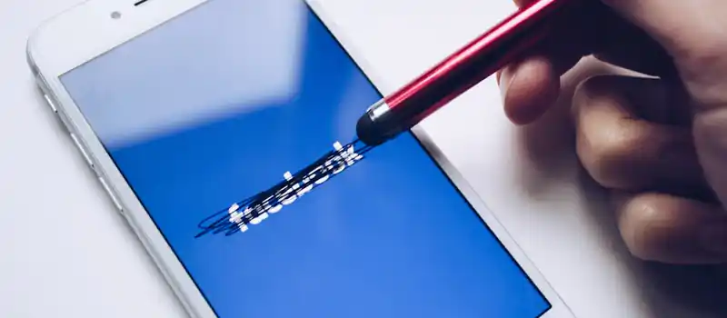 Close-up of a smartphone with a stylus crossing out text on its screen.