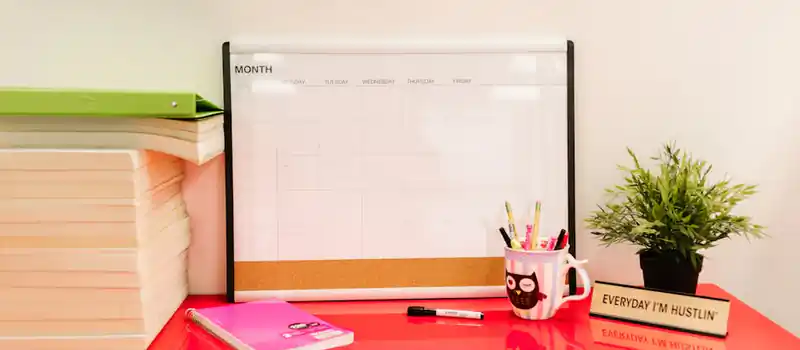 A tidy desk featuring a calendar, books, and stationery for a productive workspace.