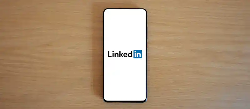Top view of a smartphone displaying the LinkedIn logo on a wooden surface.