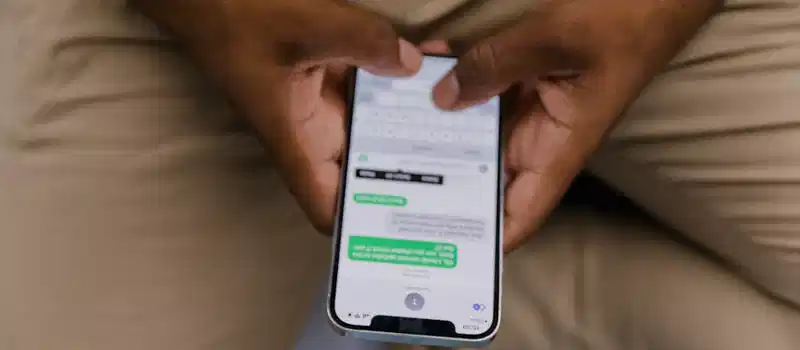 Close-up view of hands texting on a smartphone, focusing on the screen displaying messages.