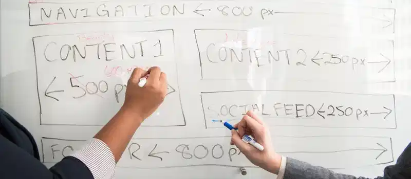 Two people collaboratively planning on a whiteboard with creative strategy.