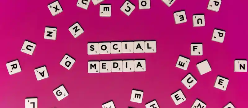 Alphabet tiles forming 'Social Media' on a vibrant pink background, perfect for digital marketing themes.