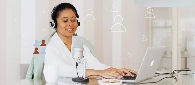 Black woman podcasting from home using a laptop and microphone.
