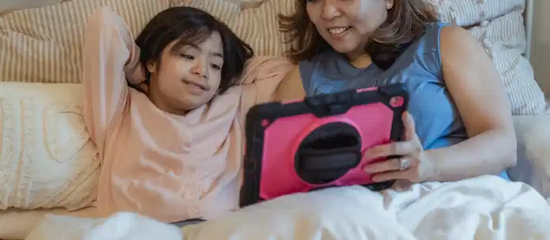 Mother and daughter bonding over a tablet in a cozy home setting.