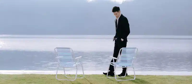 Man in a suit near a peaceful lake in Bali, Indonesia, exuding calm elegance.