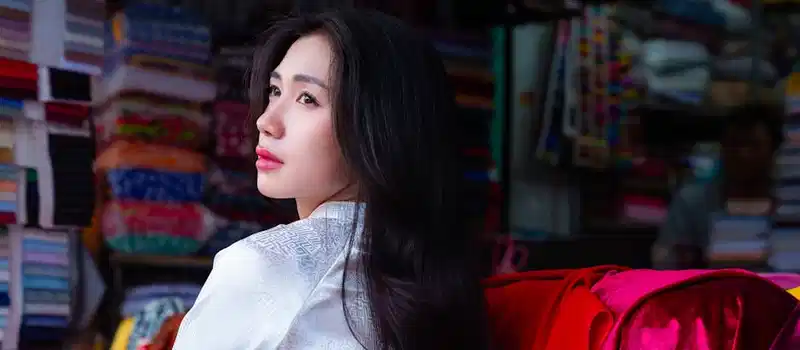 Profile of a young woman amidst colorful textiles in a fabric store, evoking creativity and fashion.