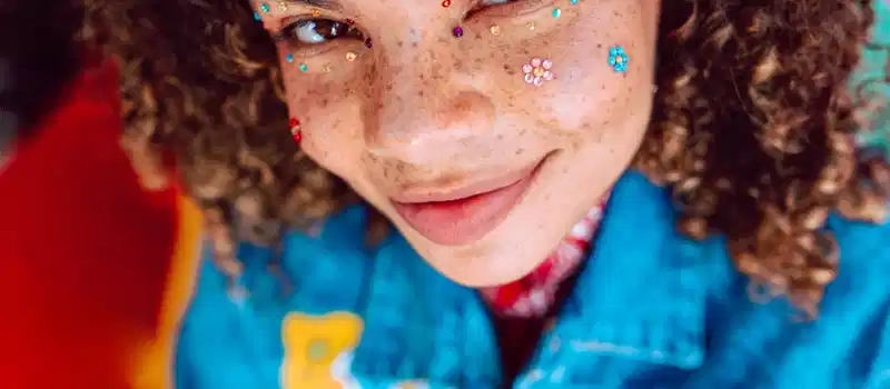Vibrant portrait featuring a young person with creative face makeup, exuding youthful joy and style.