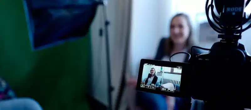 Woman being recorded in a professional studio setup, using video camera and lighting equipment.