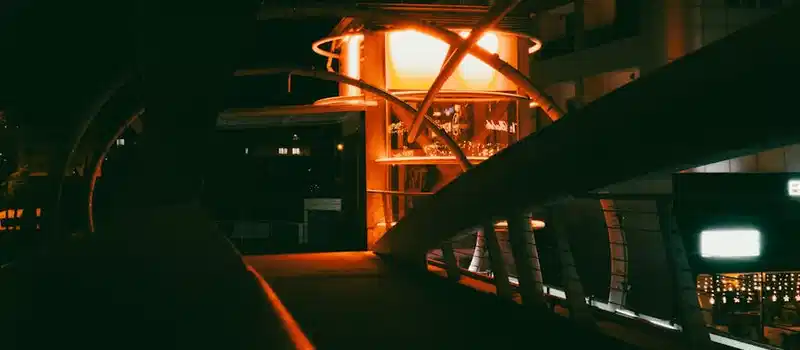 Modern bridge illuminated at night with urban architecture in background.