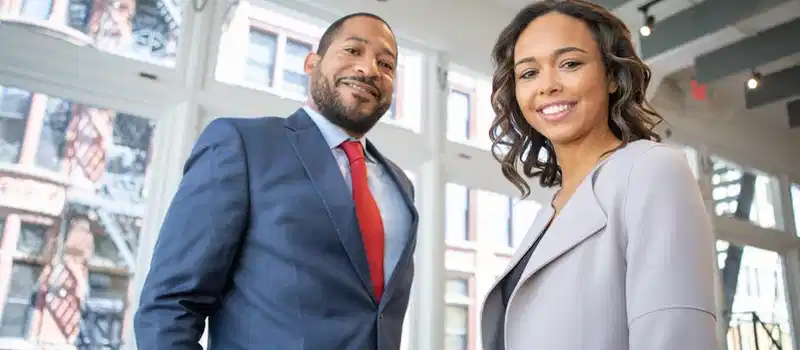 Business professionals smiling in a modern Detroit office setting.