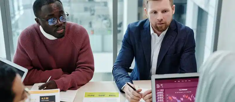 Multicultural team discussing financial data and graphs in a modern office setting.