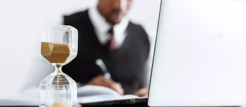 Businessman at desk with hourglass indicating time management and daily work routine.
