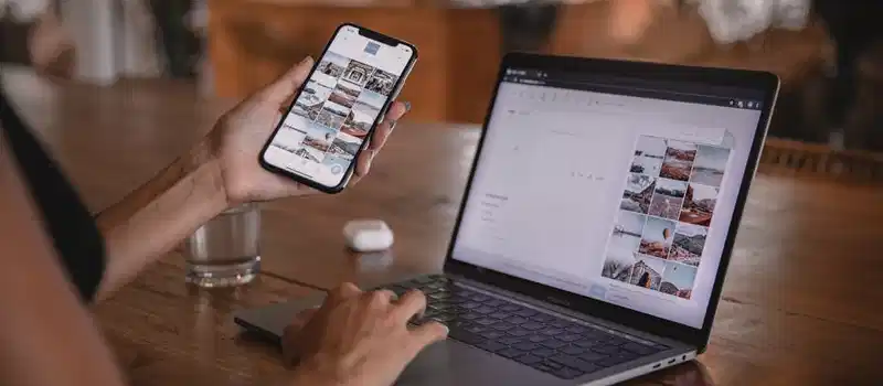 Woman edits social media content on phone and laptop at a cafe in Bali.