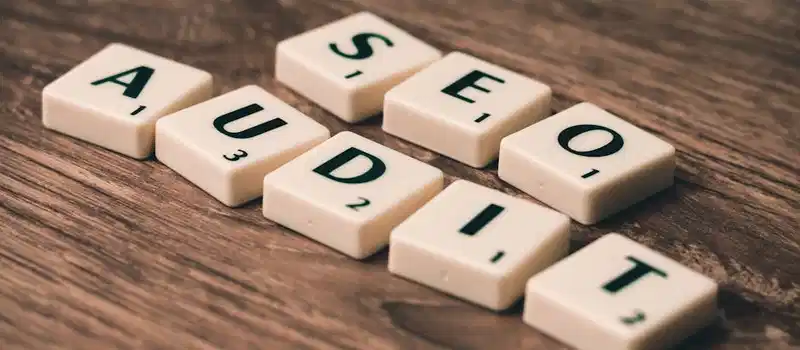 Scrabble tiles spelling SEO Audit on wooden surface, symbolizing digital marketing strategies.