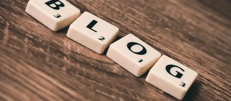 Scrabble tiles spelling 'BLOG' on a wooden background, symbolizing creativity and writing.