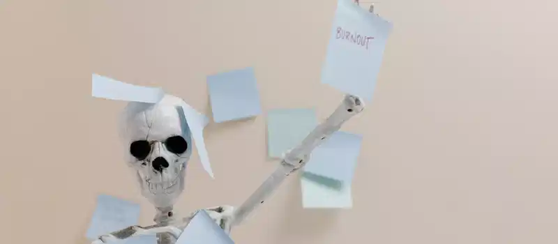 Humorous depiction of burnout with a skeleton holding sticky notes, representing overwork.
