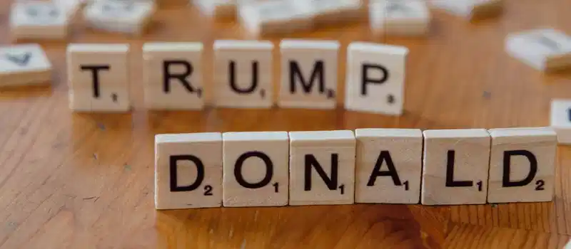 Close-up of Scrabble tiles spelling 'Donald Trump' on a wooden table.