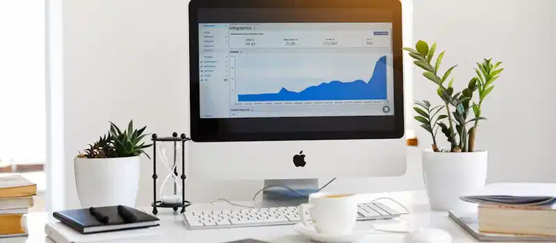 A clean, contemporary workspace featuring a desktop with analytics on the screen and plants for a fresh look.