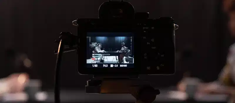 Close-up of a camera recording a podcast interview in a studio setting.