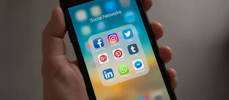 A smartphone displaying various social media icons held in a hand, showcasing modern communication apps.