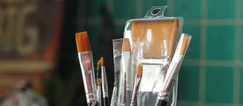 A collection of new paint brushes in a plastic container, ideal for art projects.