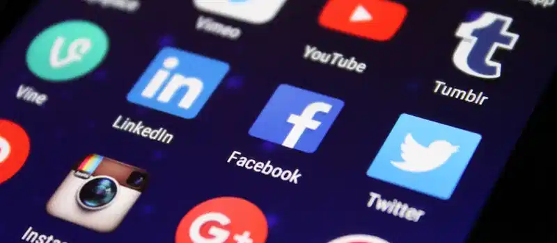 Close-up of a smartphone screen showing various social media app icons such as Facebook and Twitter.