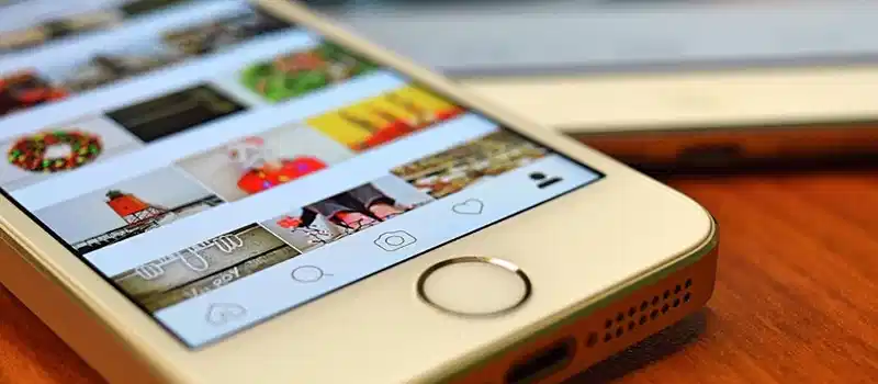 A close-up view of a smartphone displaying the Instagram app on a wooden surface.